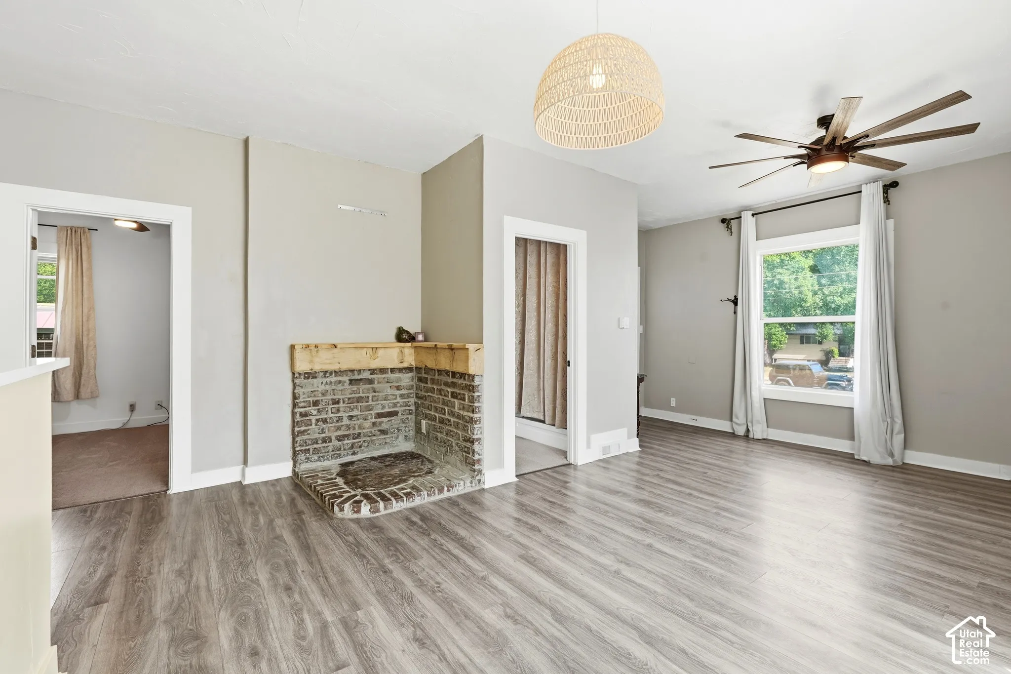 Spacious room featuring wood-finish flooring, a contemporary ceiling fan, and a woven pendant light fixture