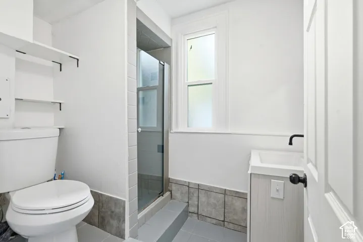 Bathroom featuring a glass-enclosed shower, white ceramic toilet, and a vanity with a wall-mounted faucet