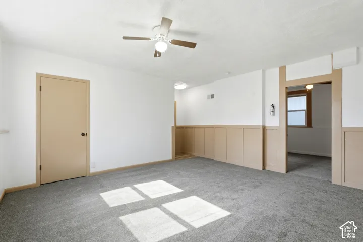 Spacious interior featuring a neutral color palette, grey carpeting, white walls, and wainscoting