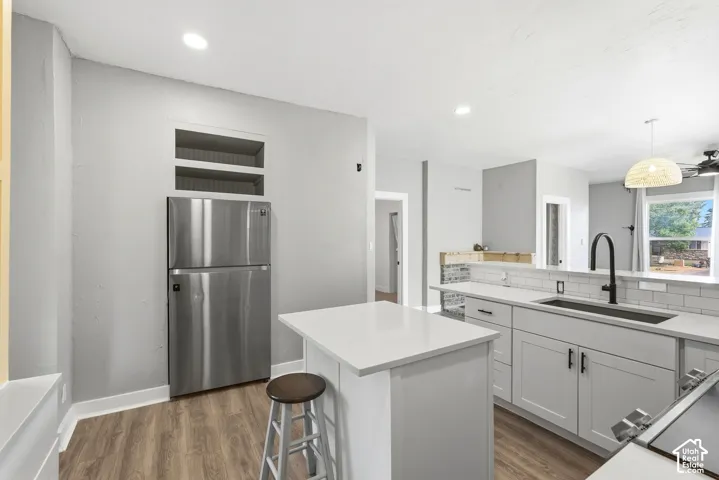 Kitchen featuring light gray cabinetry, white countertops, subway tile backsplash, and wood-finish flooring