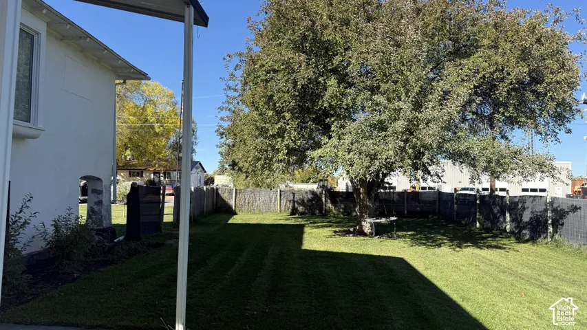 Backyard featuring a manicured lawn, mature trees, and perimeter fencing