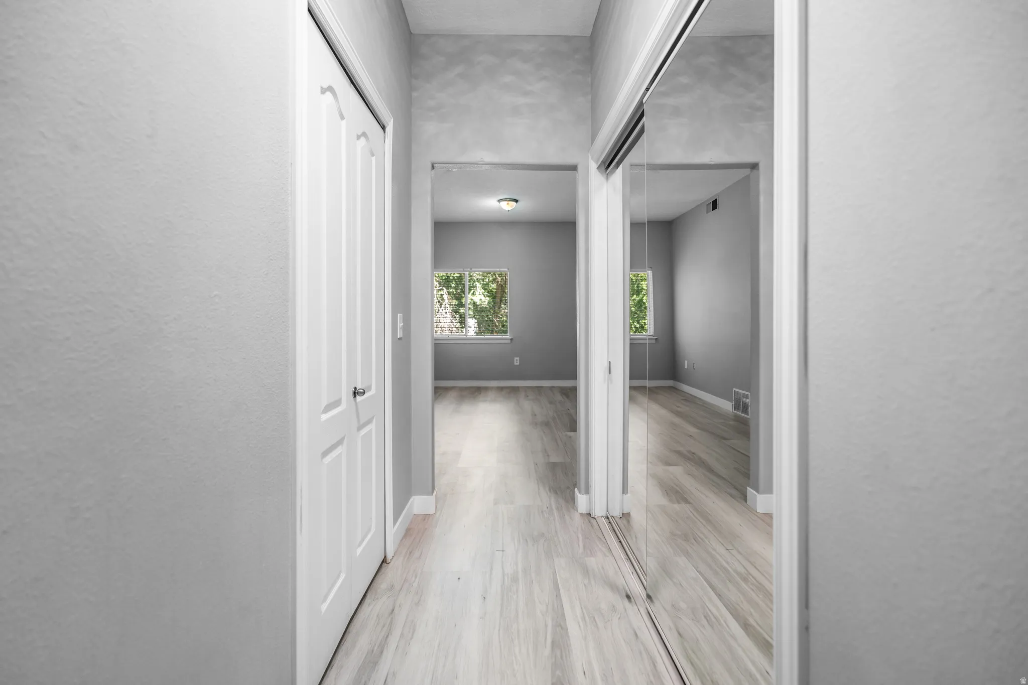 Hallway featuring wood-finish flooring, white trim, and a white six-panel door