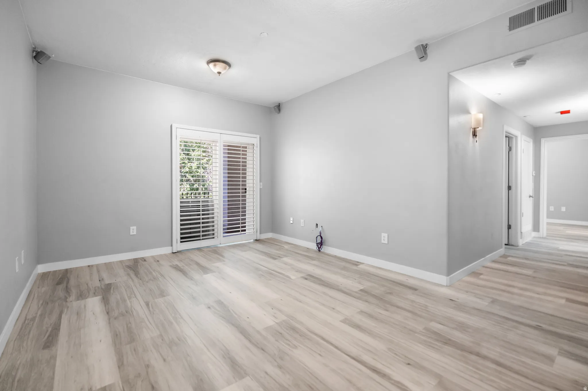 Spacious room featuring wood-finish flooring and light gray walls