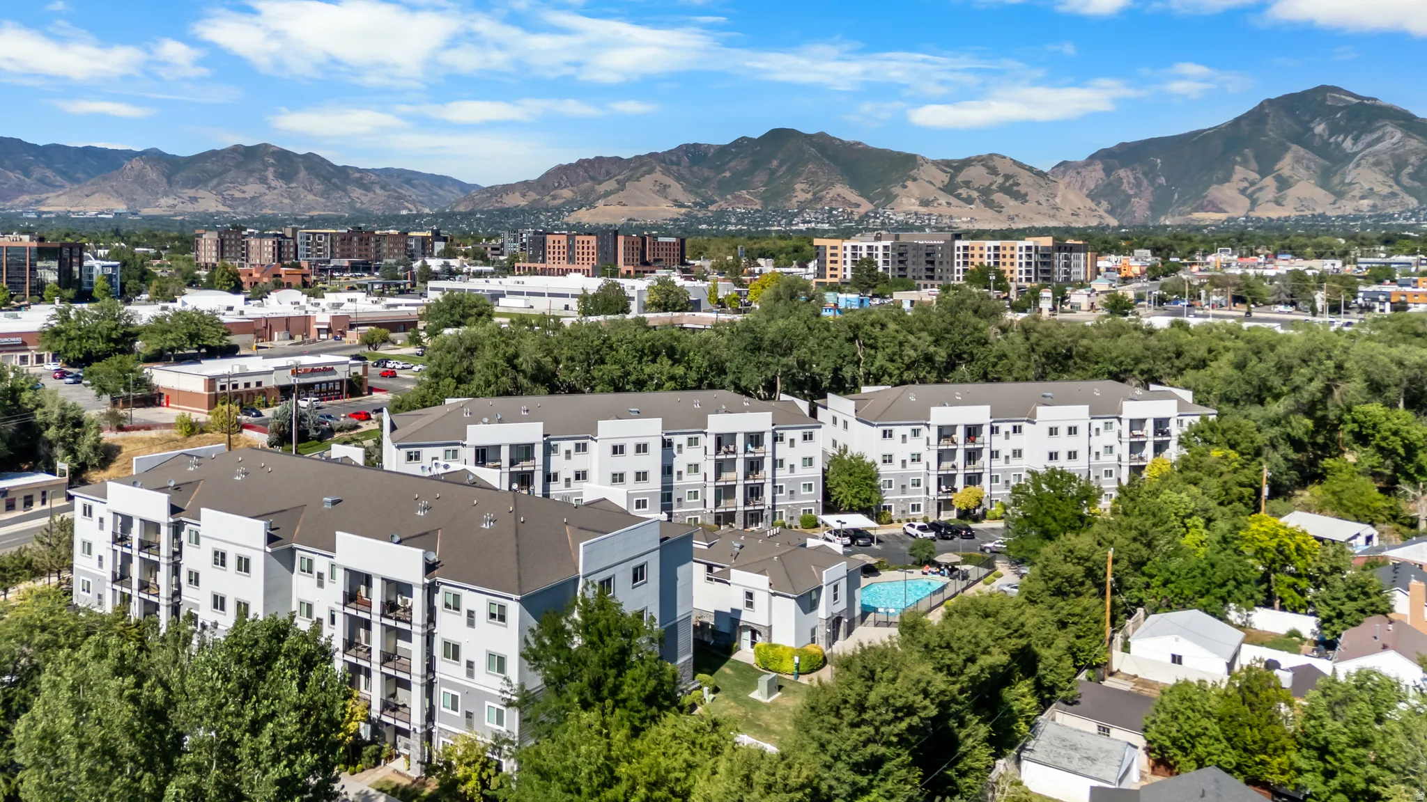Multi-story residential buildings featuring private balconies and an outdoor swimming pool