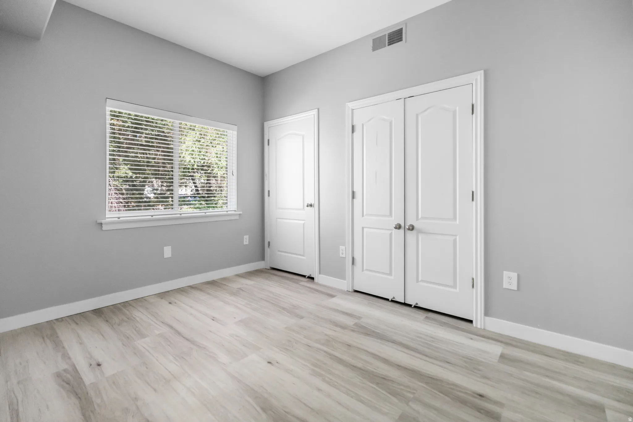 Spacious room featuring wood-finish flooring and neutral gray walls