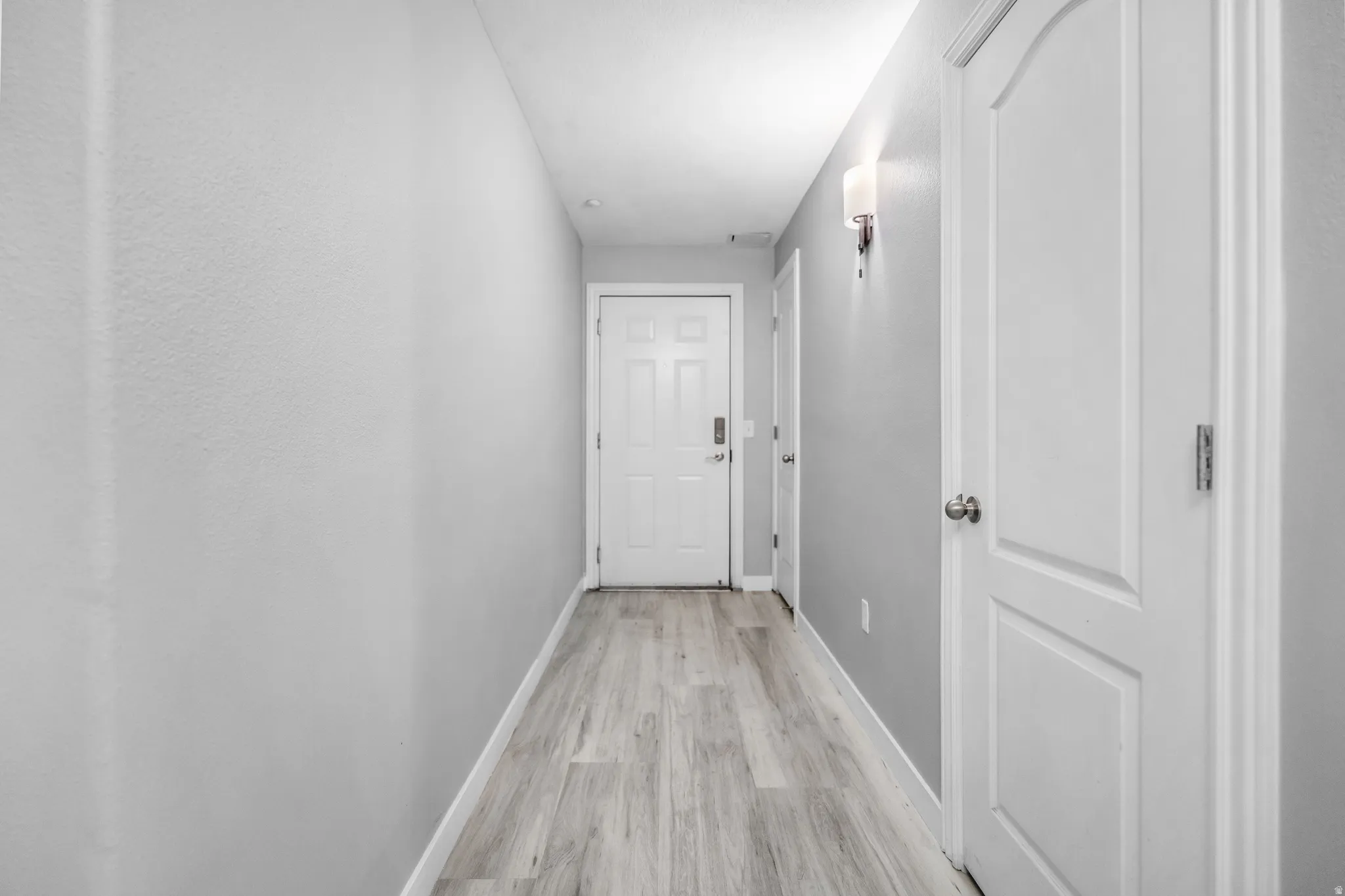 Hallway featuring wood-finish flooring, light grey painted walls, and white trim