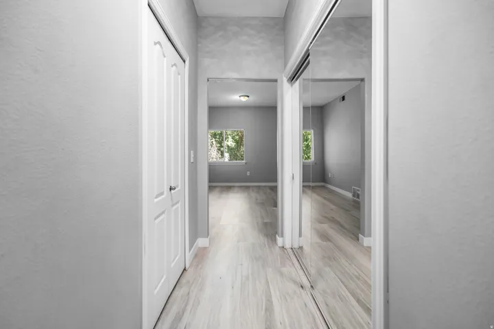 Hallway featuring wood-finish flooring, white trim, and a white six-panel door