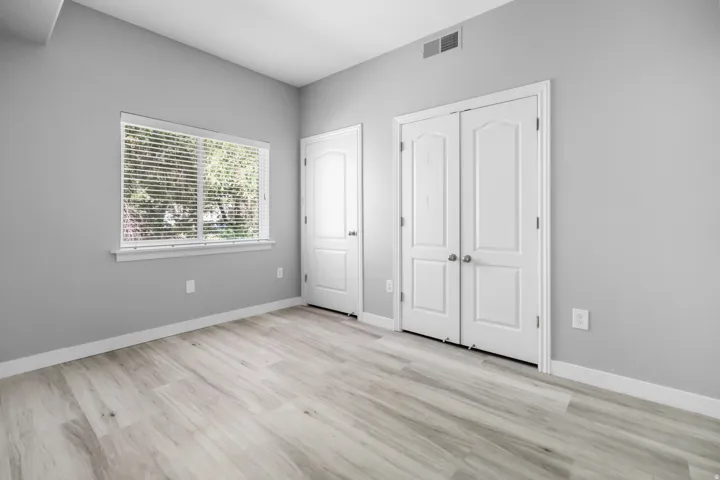 Spacious room featuring wood-finish flooring and neutral gray walls