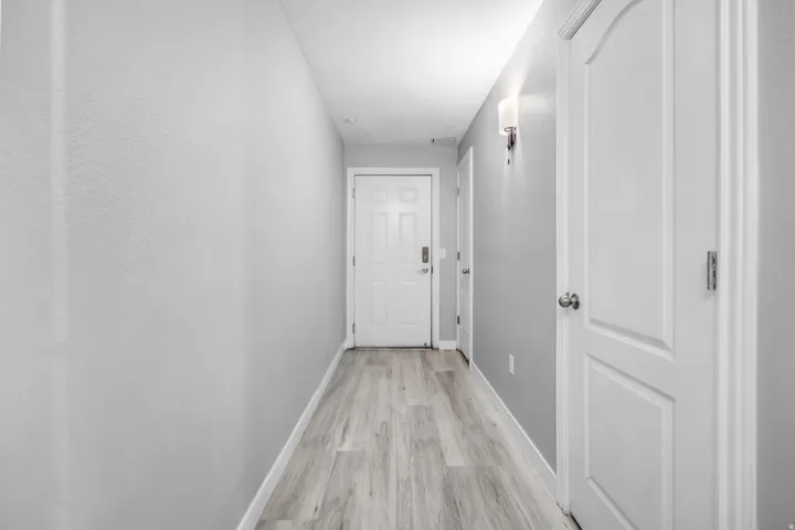 Hallway featuring wood-finish flooring, light grey painted walls, and white trim