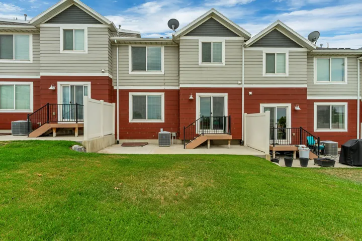 Rear exterior featuring a green lawn, concrete patio, and a privacy fence