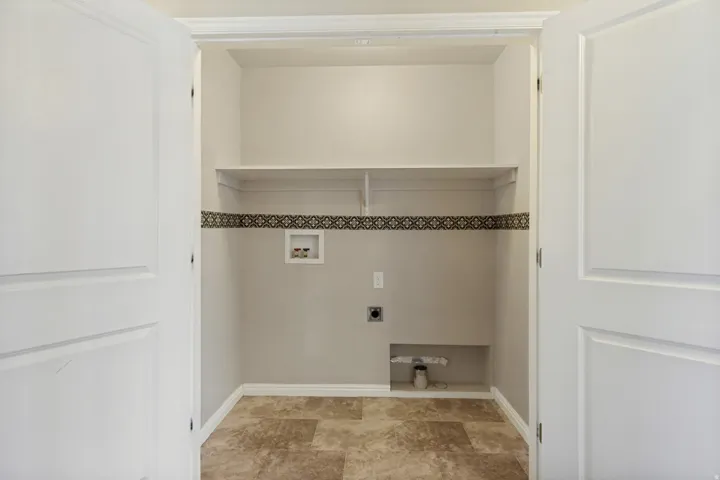 Dedicated utility space featuring a built-in shelf, decorative wall trim, and a recessed appliance area