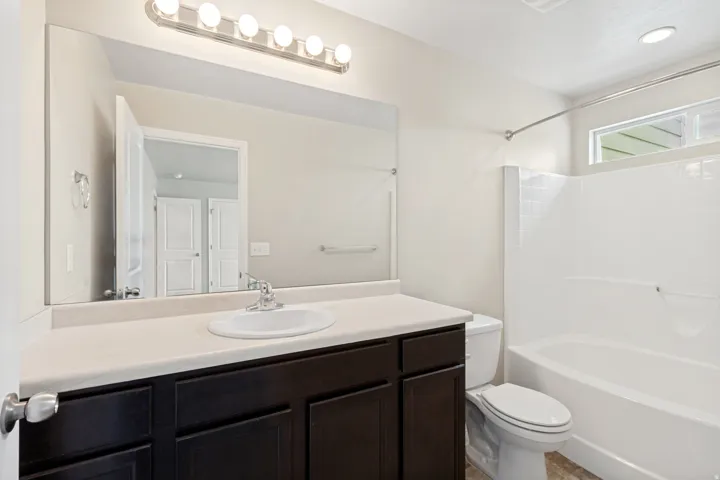 Bathroom featuring a dark wood-finish vanity, a spacious countertop, an integrated sink, and a built-in shower and tub combination