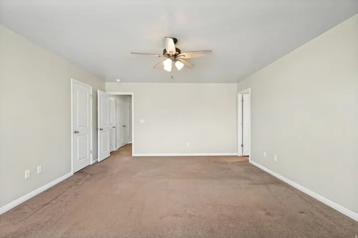 Expansive room featuring neutral-toned carpet flooring, light wall paint, and white trim