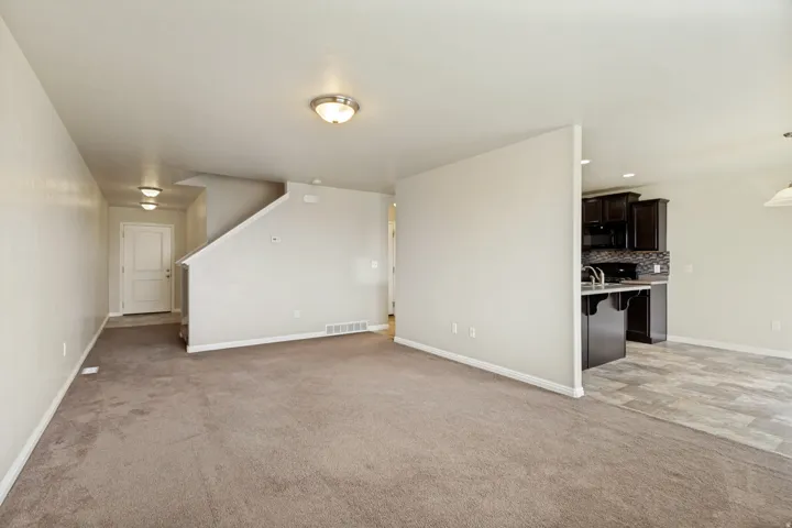 Open concept living area featuring neutral carpeting and light wall tones