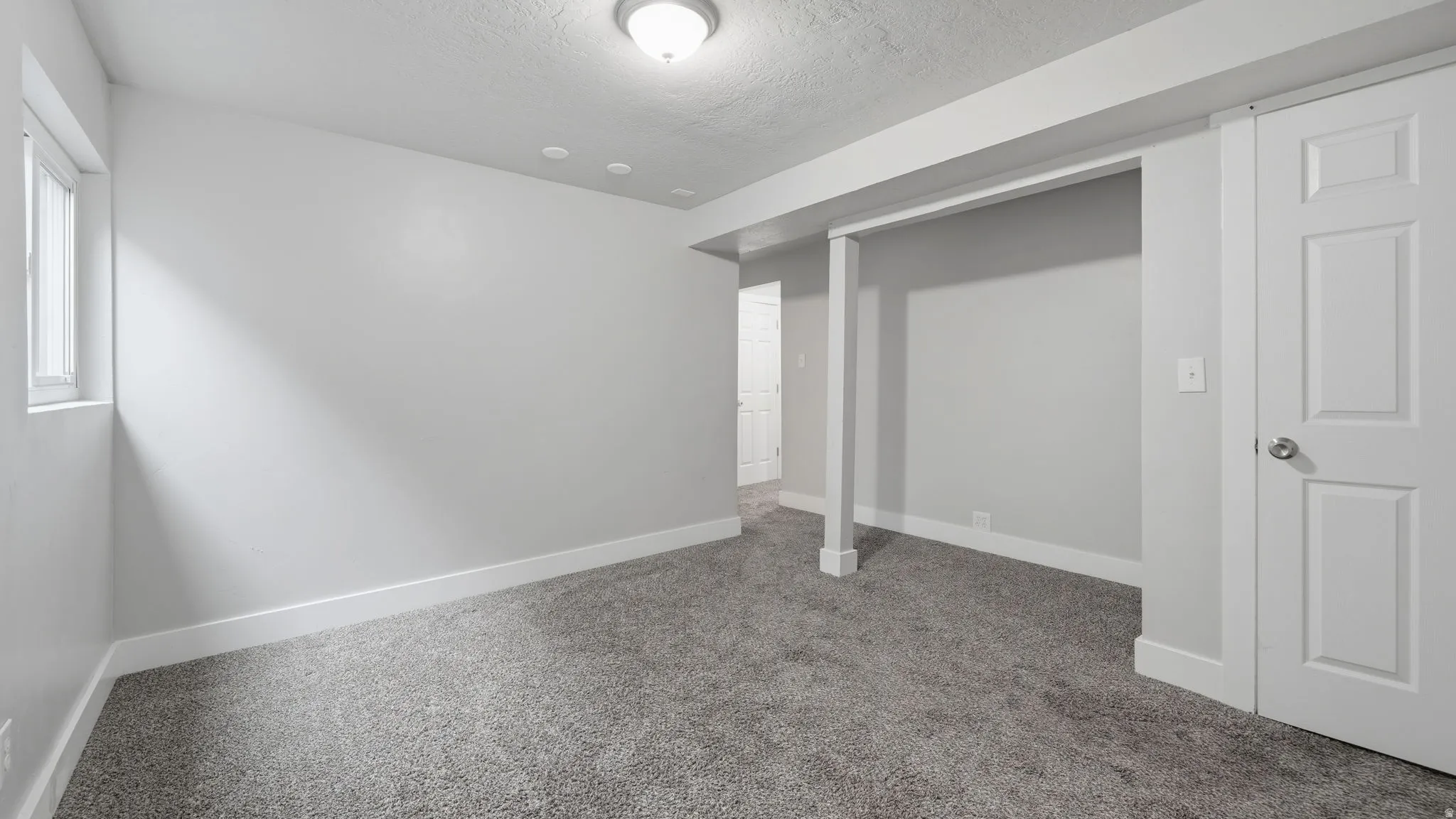 Spacious carpeted multi-purpose room off stairs from main level, could be family room, den, office or other multi-use gathering space.
