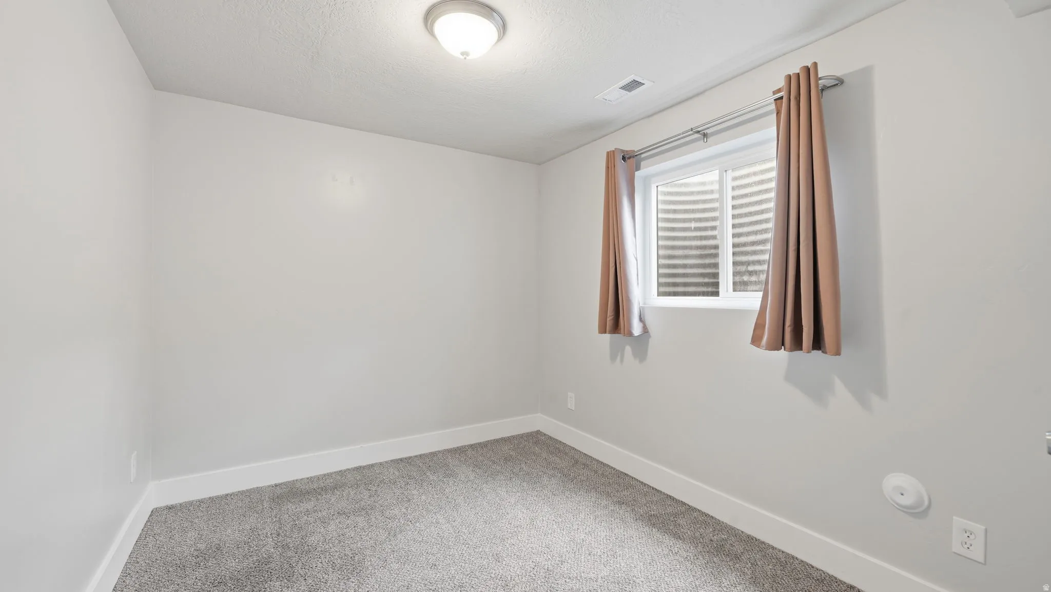 Carpeted bedroom downstairs with closet and window.