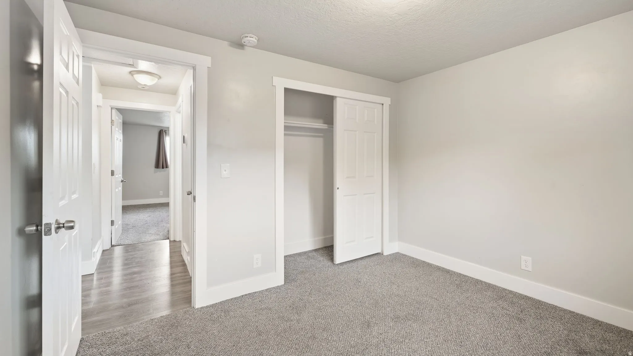Carpeted bedroom with multiple outlets, window, and closet with sliding door panels.