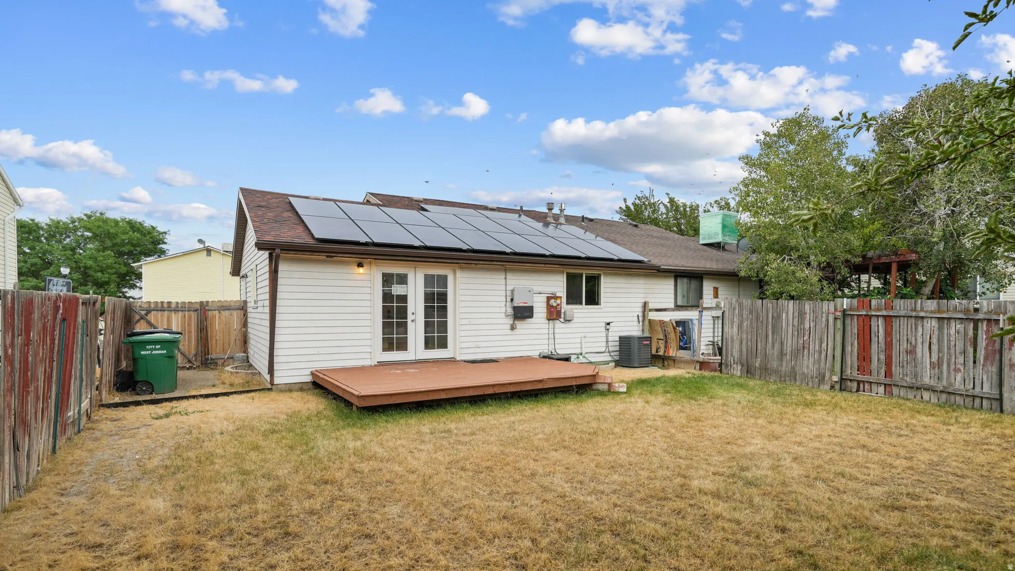 Rear exterior featuring a wood deck, solar panels and fencing, along with side yard space.