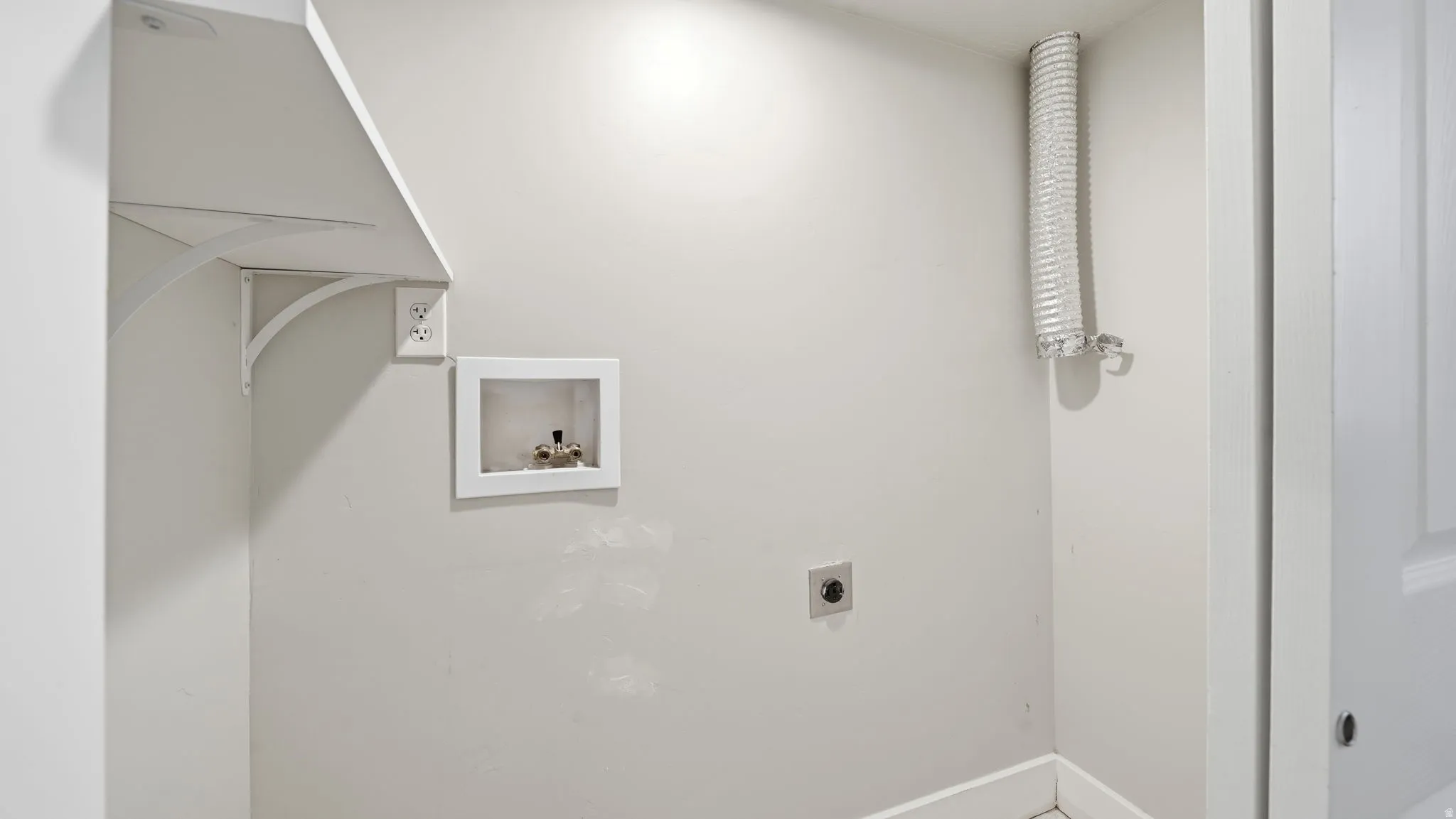 Dedicated laundry area featuring a wall-mounted shelf, electrical outlet, and plumbing hookups