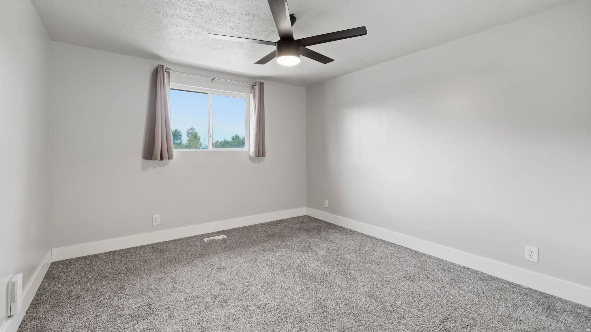 Spacious carpeted bedroom, ceiling fan with integrated lighting, closet with sliding panels, and a double window with mountain views.