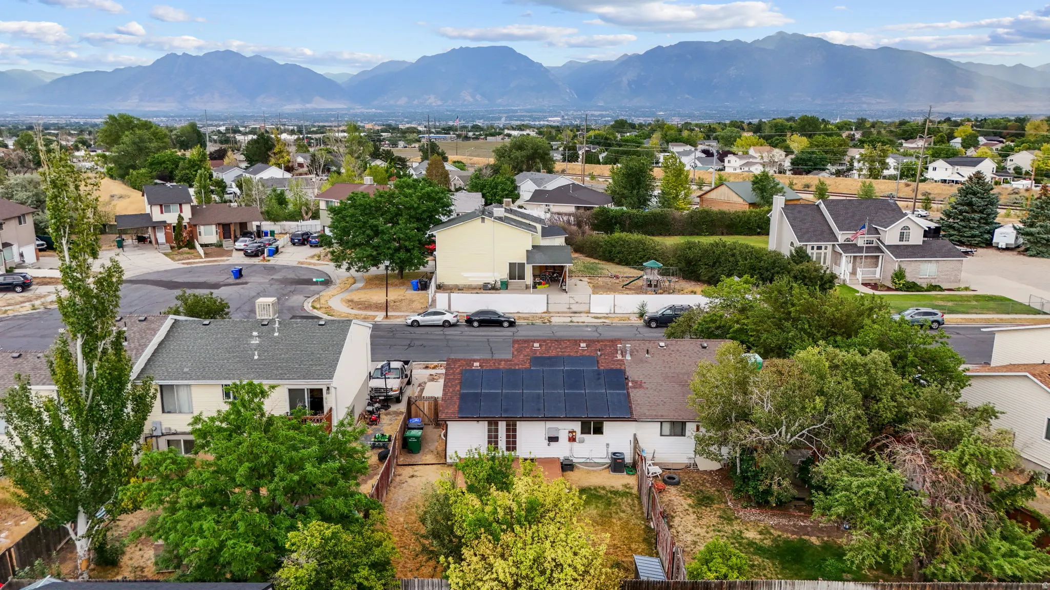 Aerial view of backyard and solar panels, residential neighborhoods, with views of the Wasatch mountains.