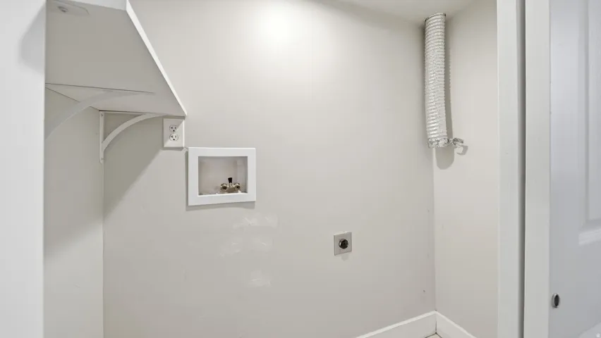 Dedicated laundry area featuring a wall-mounted shelf, electrical outlet, and plumbing hookups