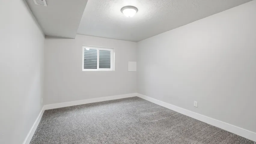 Carpeted bedroom downstairs with closet and window.