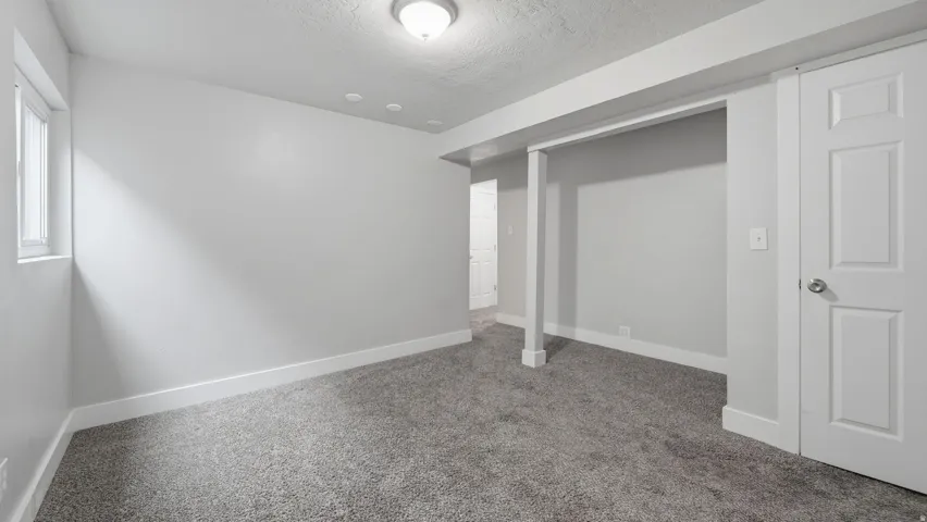 Spacious carpeted multi-purpose room off stairs from main level, could be family room, den, office or other multi-use gathering space.