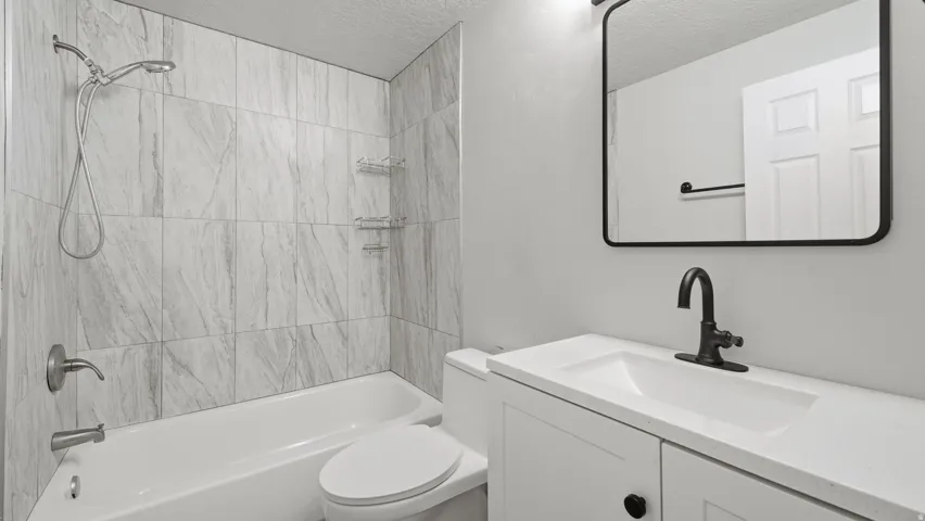 Full bathroom with contemporary tile design and white vanity.
