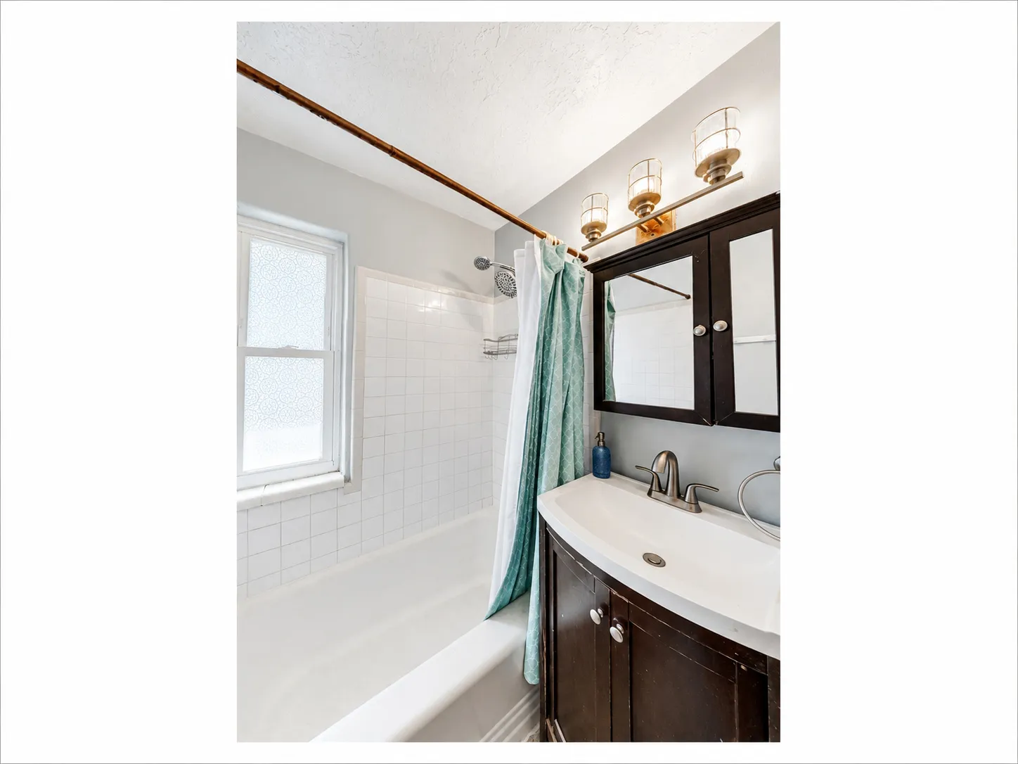 Bathroom featuring a dark wood vanity with an integrated sink, a matching medicine cabinet, and a three-light fixture