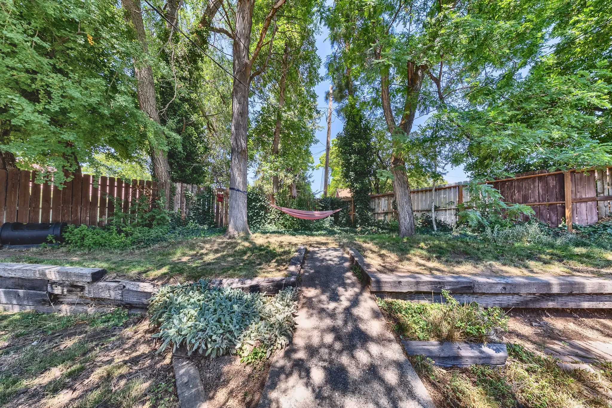 Tiered backyard featuring mature trees, wood privacy fencing, and concrete steps
