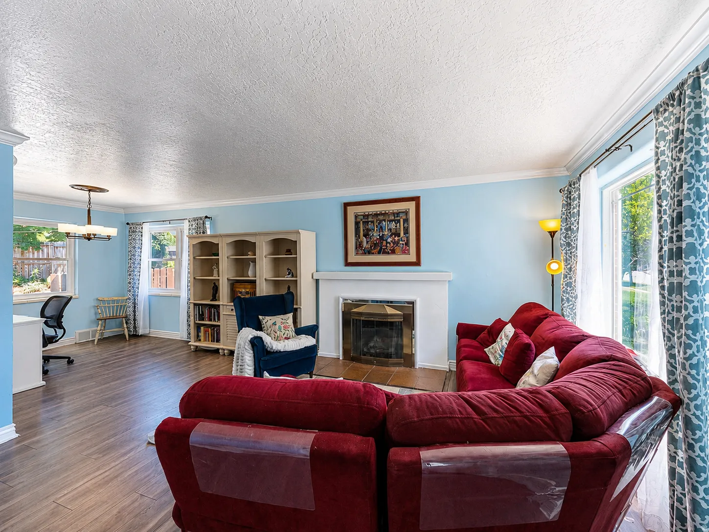 Living space featuring wood-finish flooring, a fireplace with a white mantel, and an adjacent built-in shelving unit