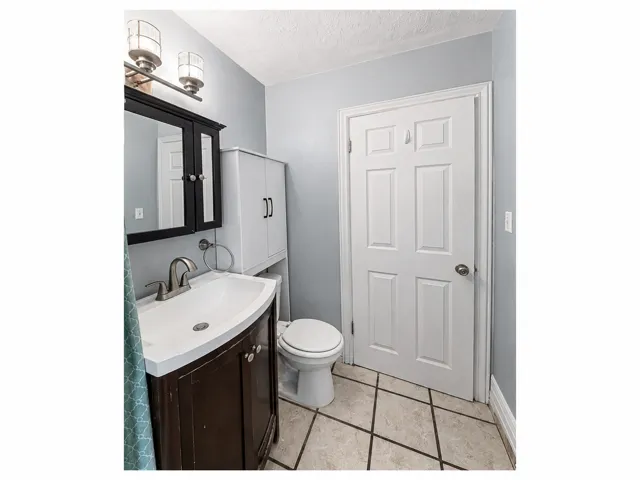 Bathroom featuring a dark wood vanity with white sink, white medicine cabinet, and a white six-panel door