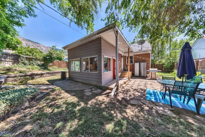 Exterior living space featuring a stone patio and an additional structure with multiple windows
