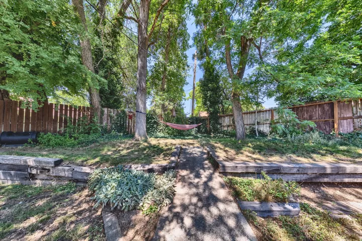 Tiered backyard featuring mature trees, wood privacy fencing, and concrete steps