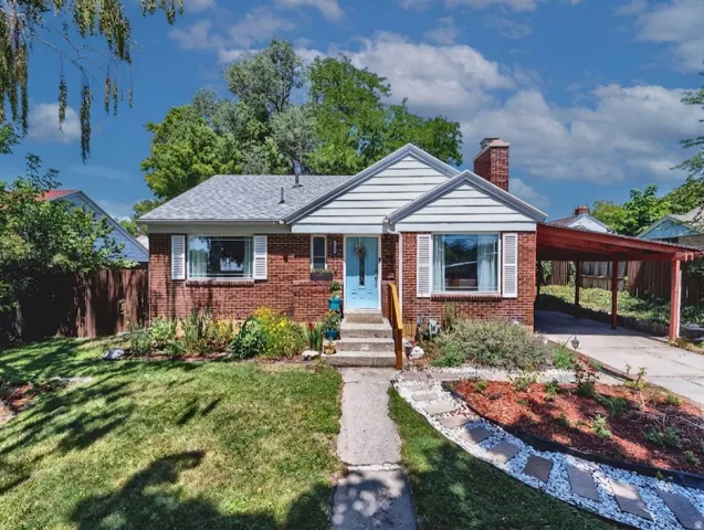 Red brick exterior, white siding accents, concrete pathway, carport, and landscaped front yard