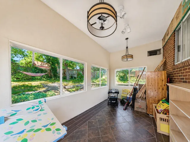 Sunroom with high ceilings, large windows, recessed lighting, two decorative light fixtures, and tiled flooring