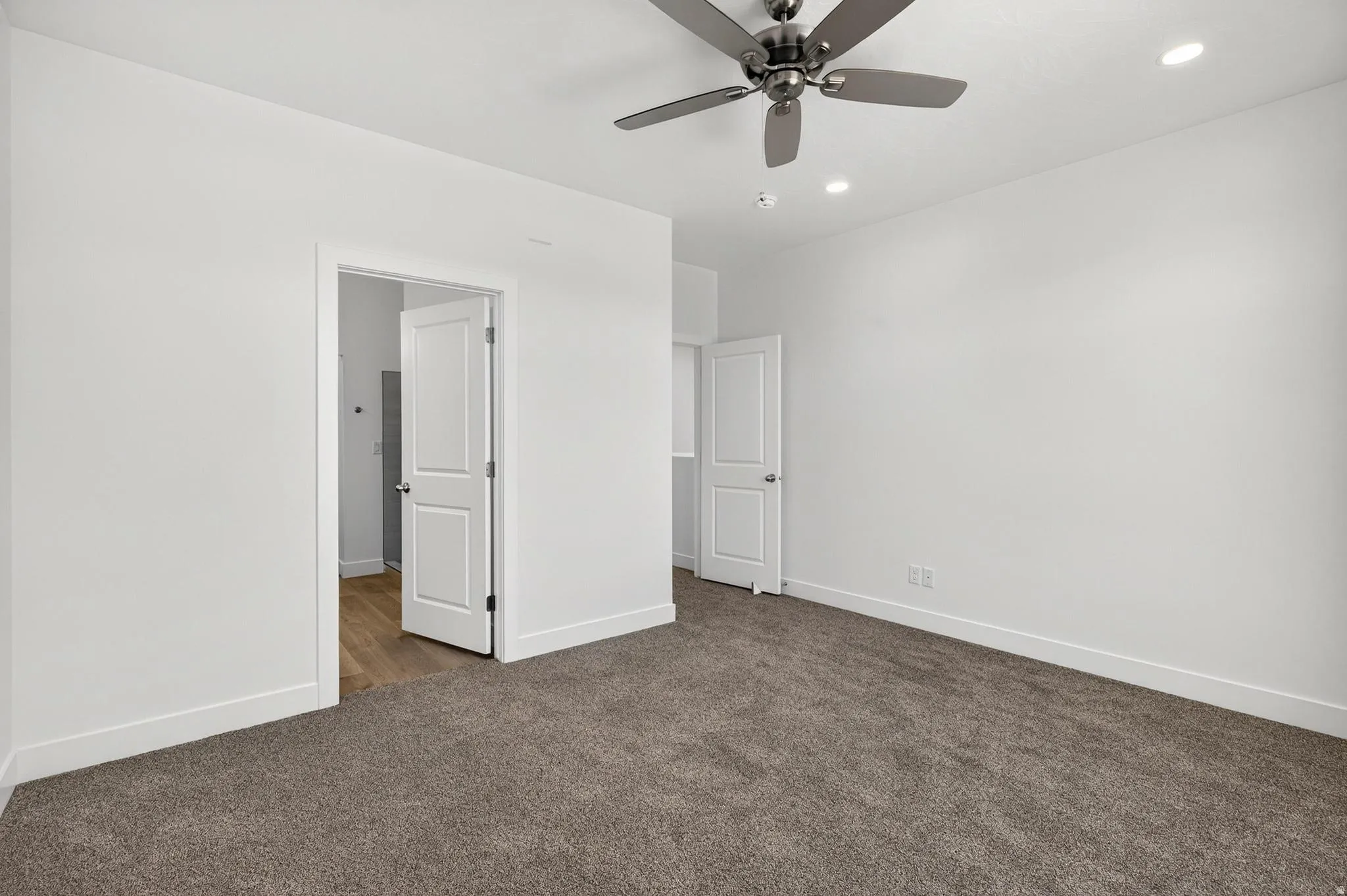 Spacious room featuring neutral-toned carpeting, white walls, and bright white trim