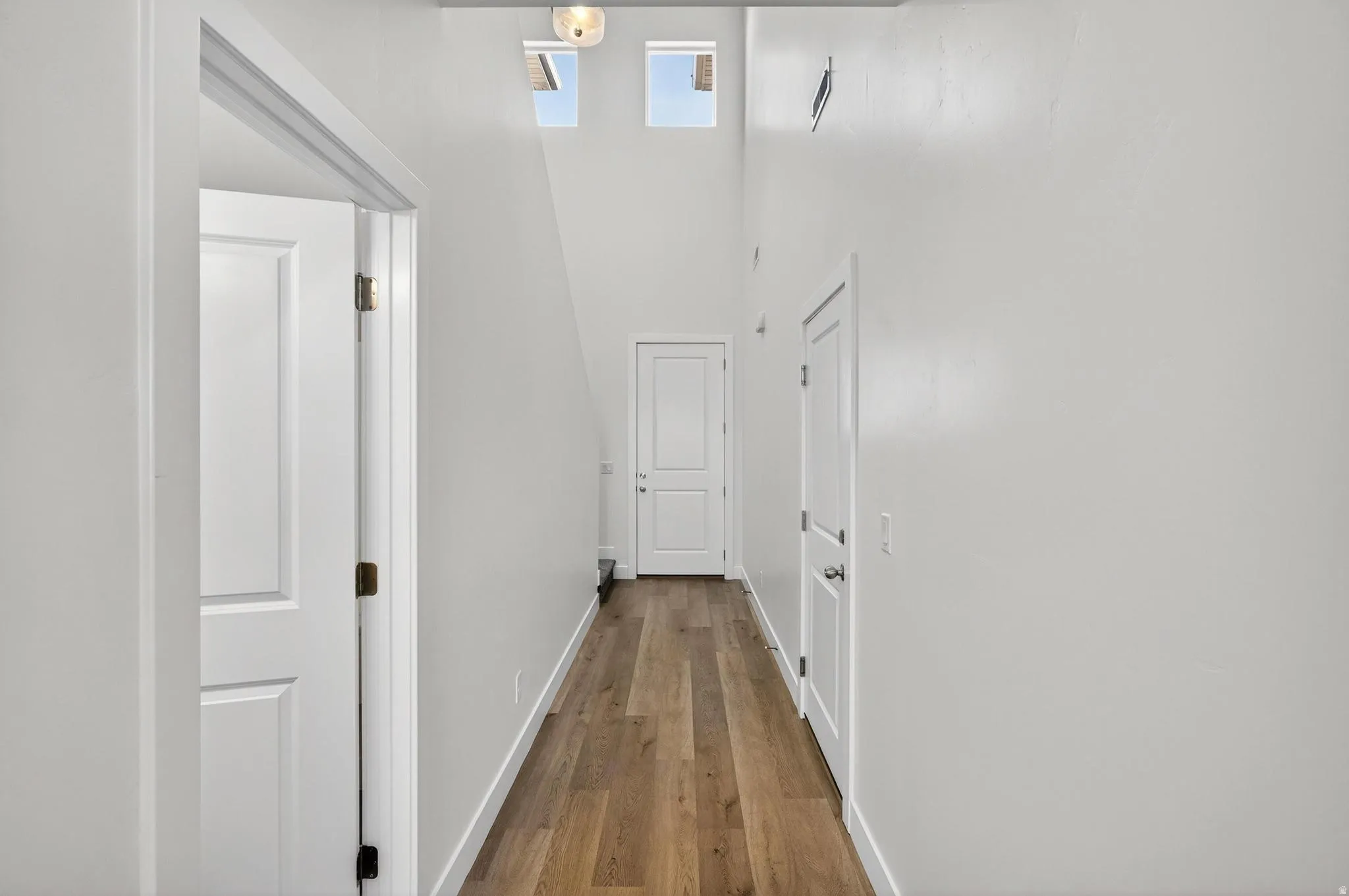 Hallway featuring wood-finish flooring, white walls, and recessed lighting