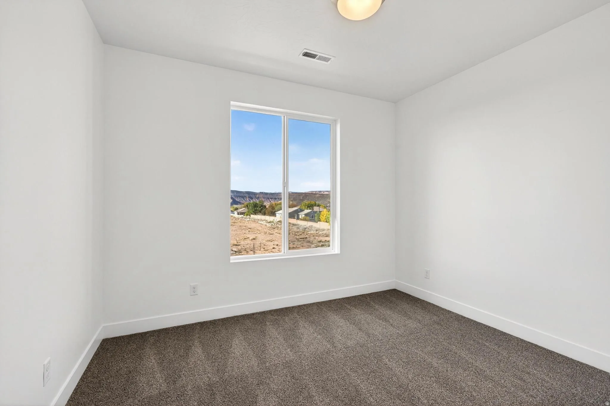 Room featuring a large picture window, neutral wall paint, and patterned carpet flooring