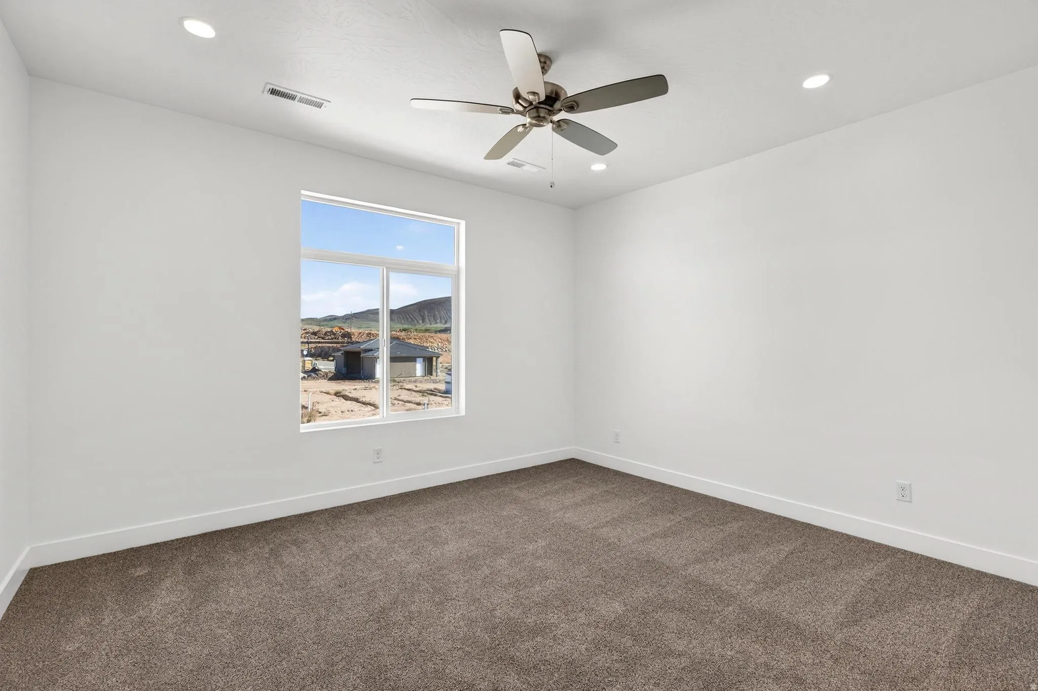 Spacious room featuring a large picture window, recessed lighting, and a ceiling fan