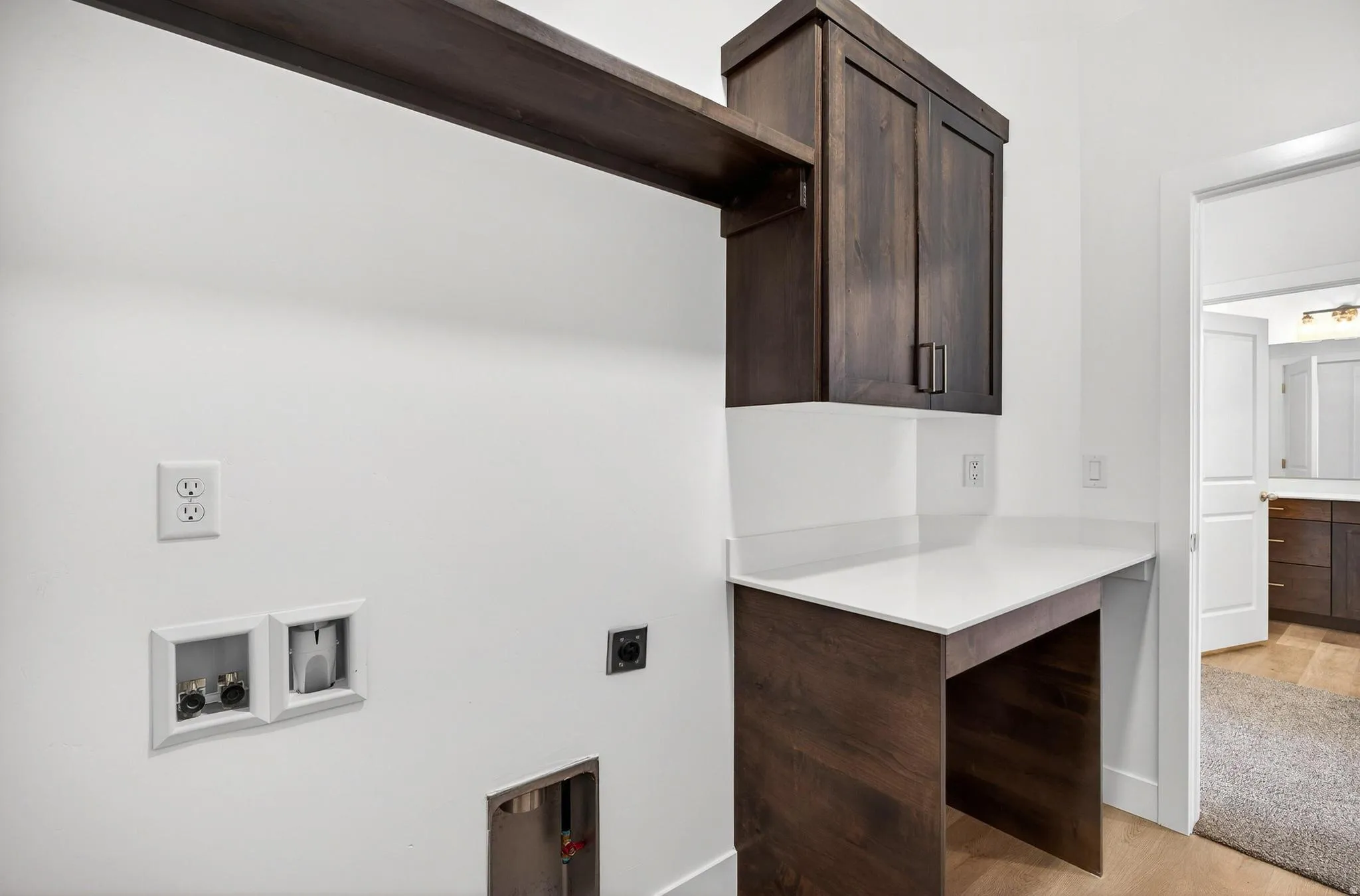 Dedicated laundry area featuring dark wood-finish cabinetry, a white countertop, and wood-finish flooring