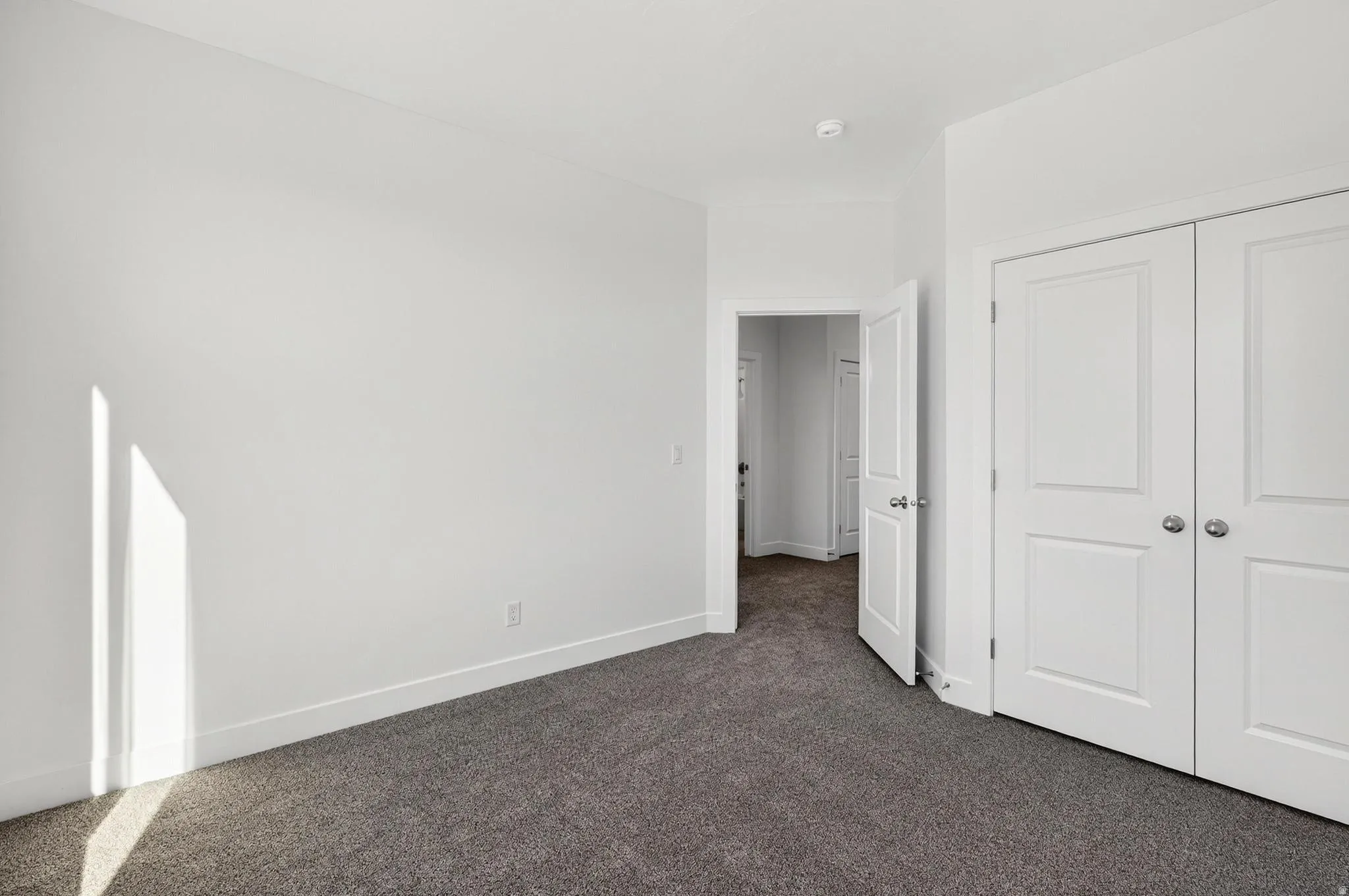 Room featuring plush grey carpeting, white walls, and bright white trim