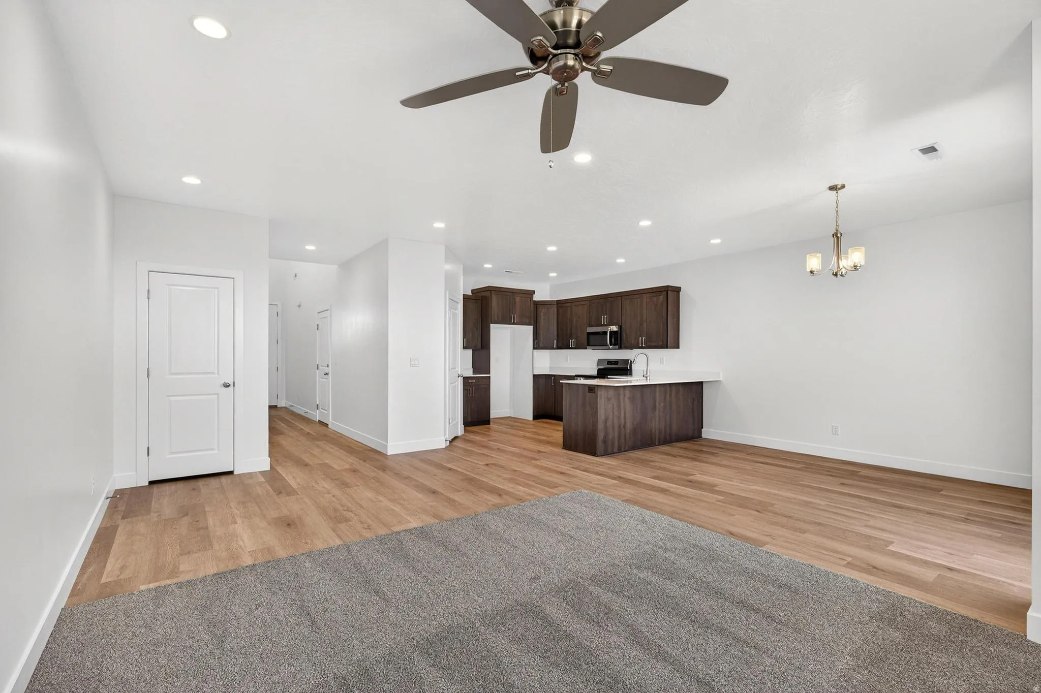 Open-concept living space featuring wood-finish flooring, recessed lighting, and a ceiling fan