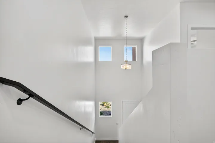 Two-story foyer with high ceilings, multiple square windows, and a black handrail