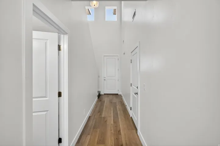 Hallway featuring wood-finish flooring, white walls, and recessed lighting