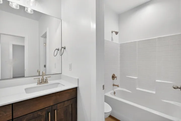 Bathroom featuring a built-in vanity with dark wood-finish cabinetry, a white countertop, and an integrated sink with a brushed nickel faucet