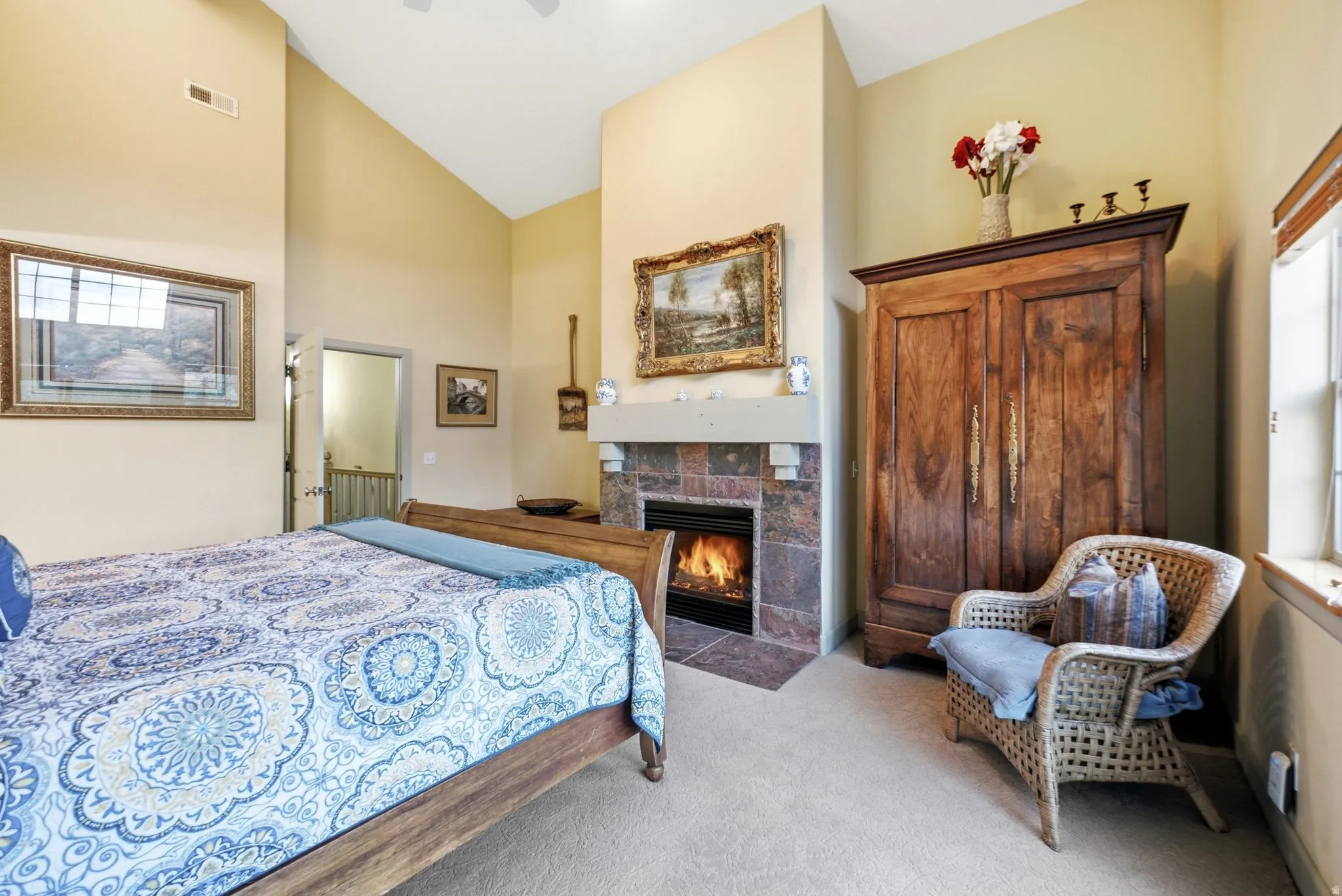 Vaulted ceiling bedroom with a stone-surround fireplace, mantle, and recessed lighting