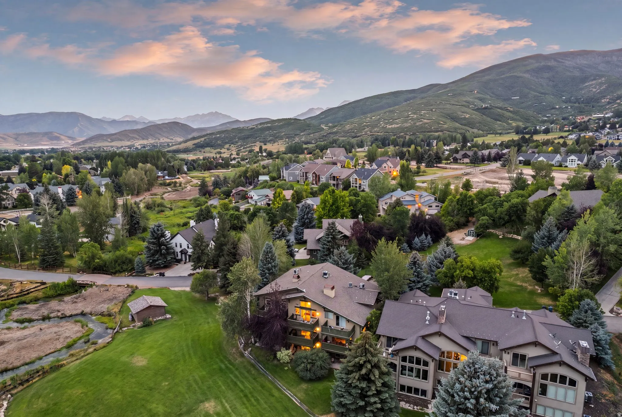 Expansive landscape featuring an elevated residential area with mature trees and mountain scenery