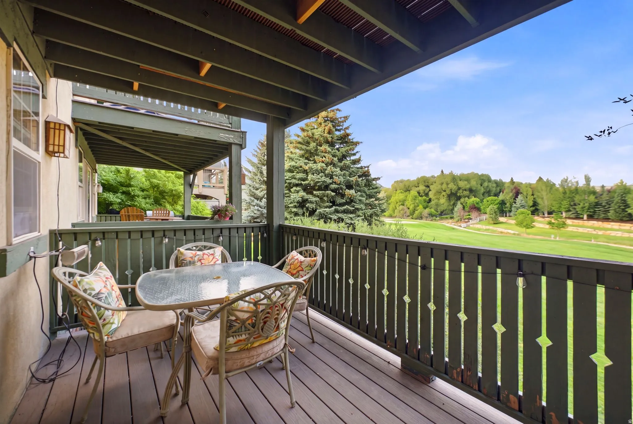Covered outdoor deck featuring composite decking and a decorative wood railing